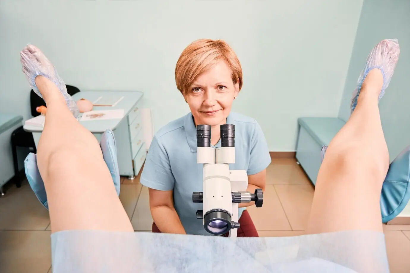 A kind gynecologist performing an examination of a female patient in a clinic.