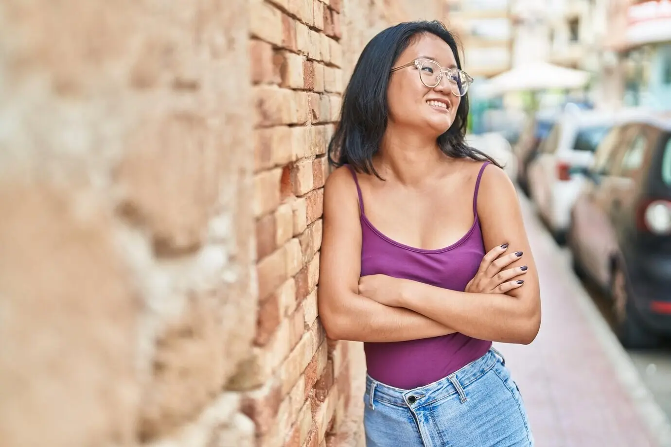 A young Chinese woman standing on the street with her arms crossed.